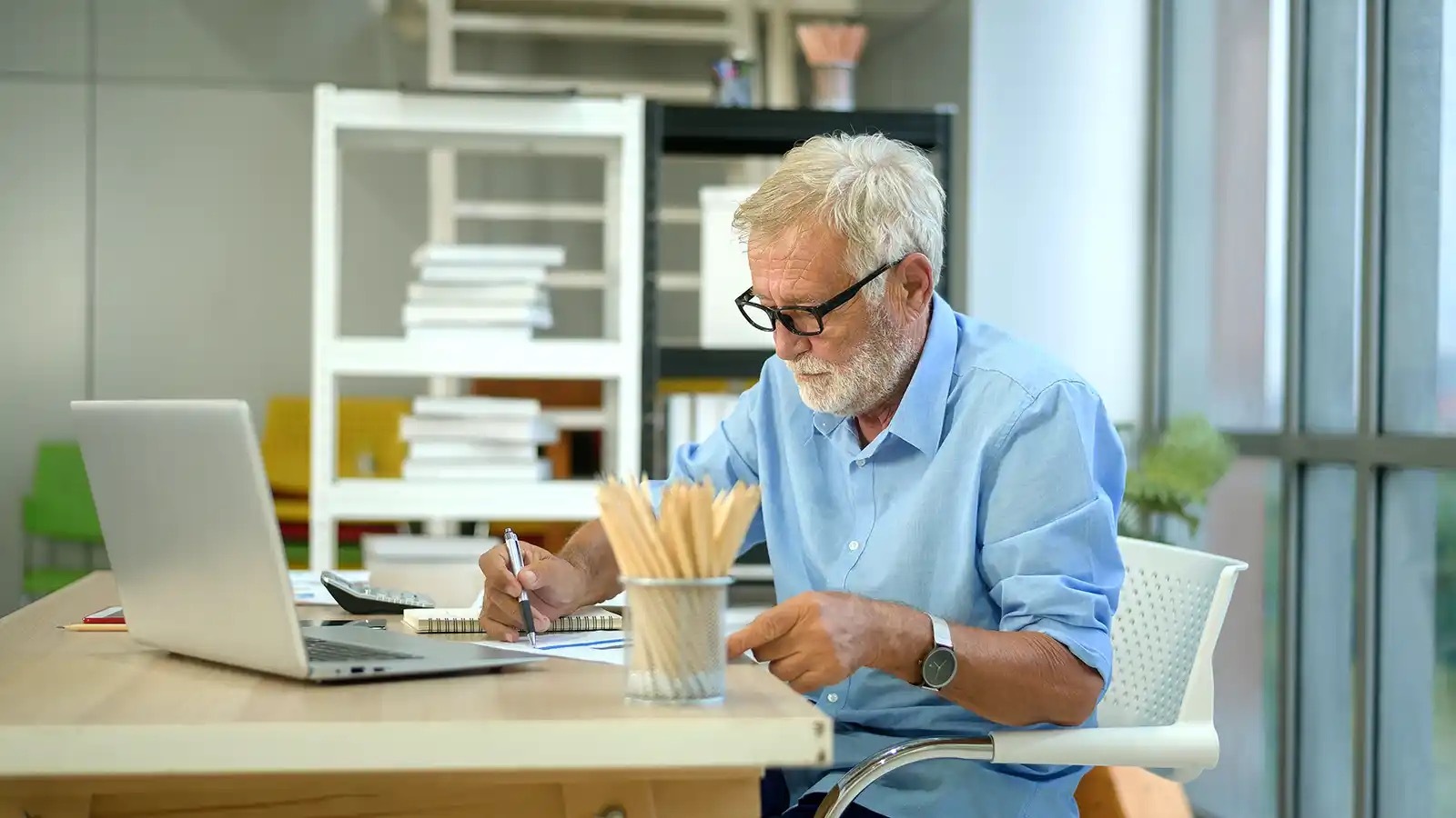 A man with sharp, modern glasses working on a spreadsheet.