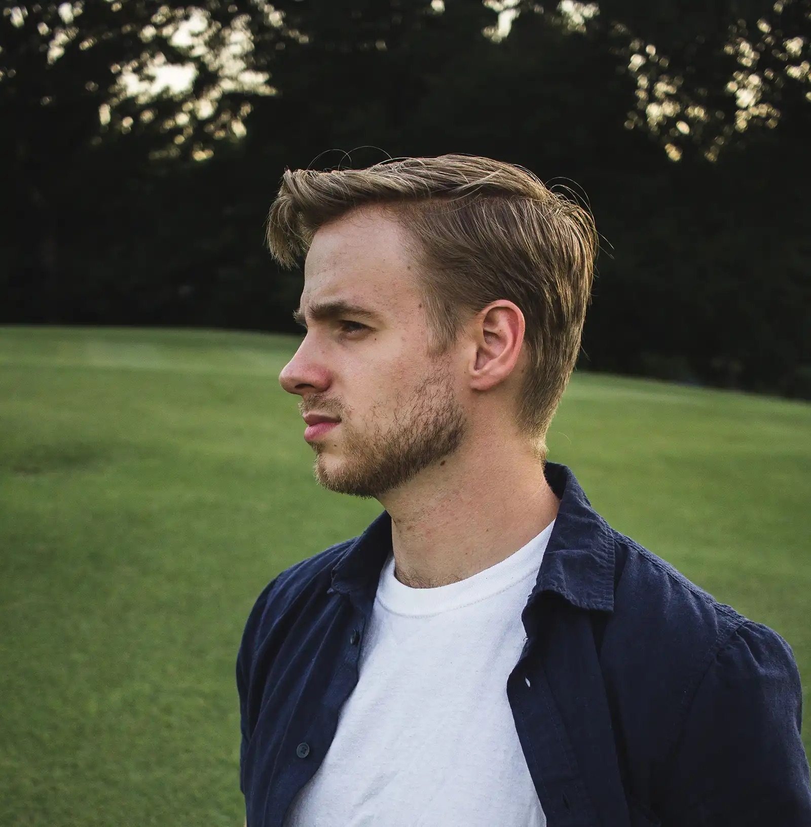Young, blonde college student male with a thoughtful look on his face.