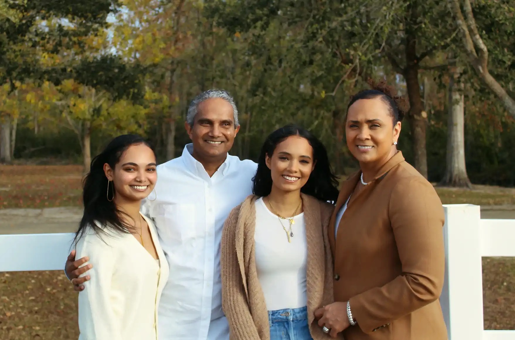 Family portrait with two college students leaning happily with their older parents.