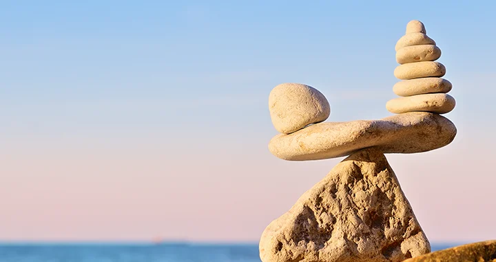 Small, stacked rocks balancing perfectly on the top of a larger rock overlooking an ocean